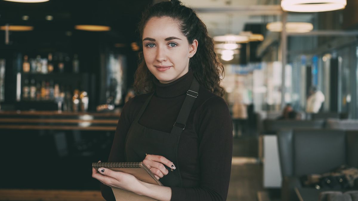 Kvinne med forkle jobber deltid i kafé