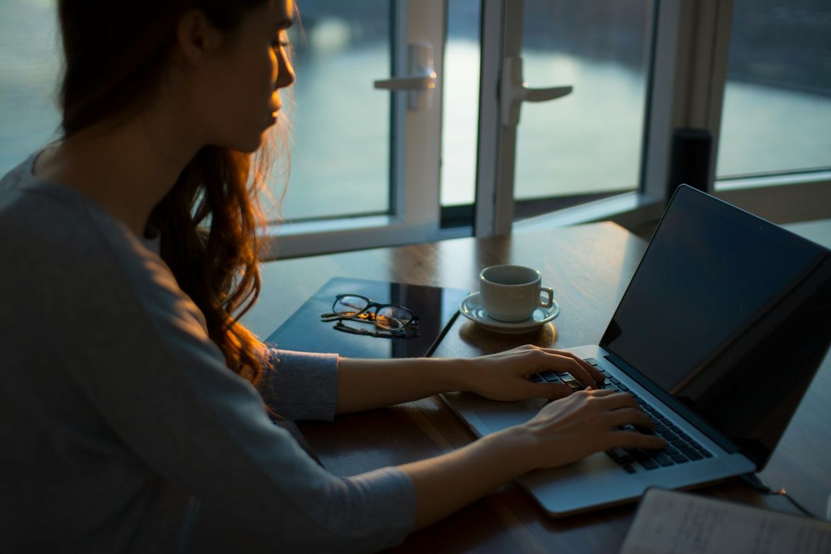 Kvinne med kaffe og laptop i rolige omgivelser