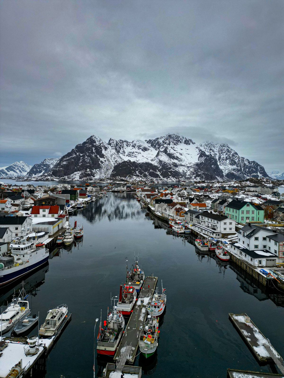 Fiskebåter i havn under snødekte fjell i Lofoten