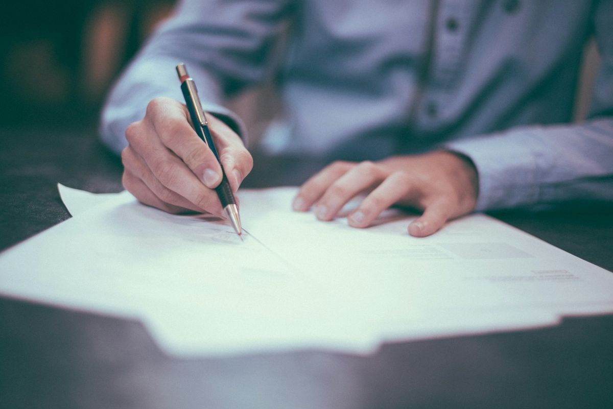 Person signerer kontrakt med penn