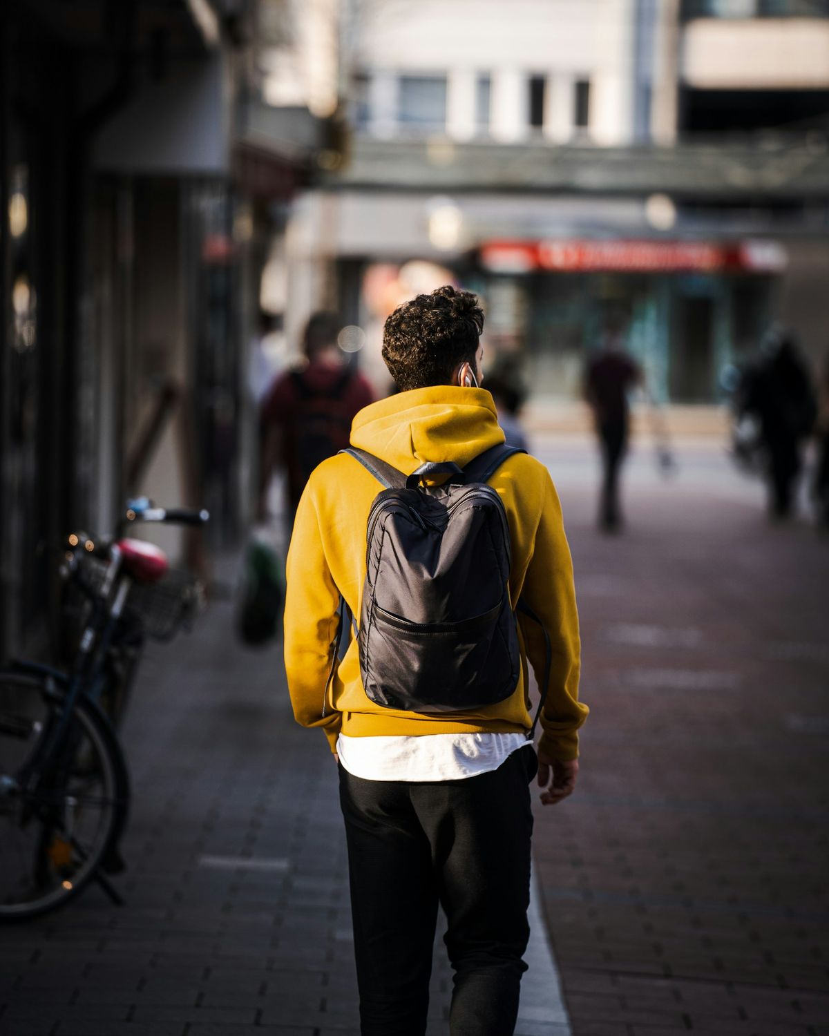 Ung person med ryggsekk går langs fortauet