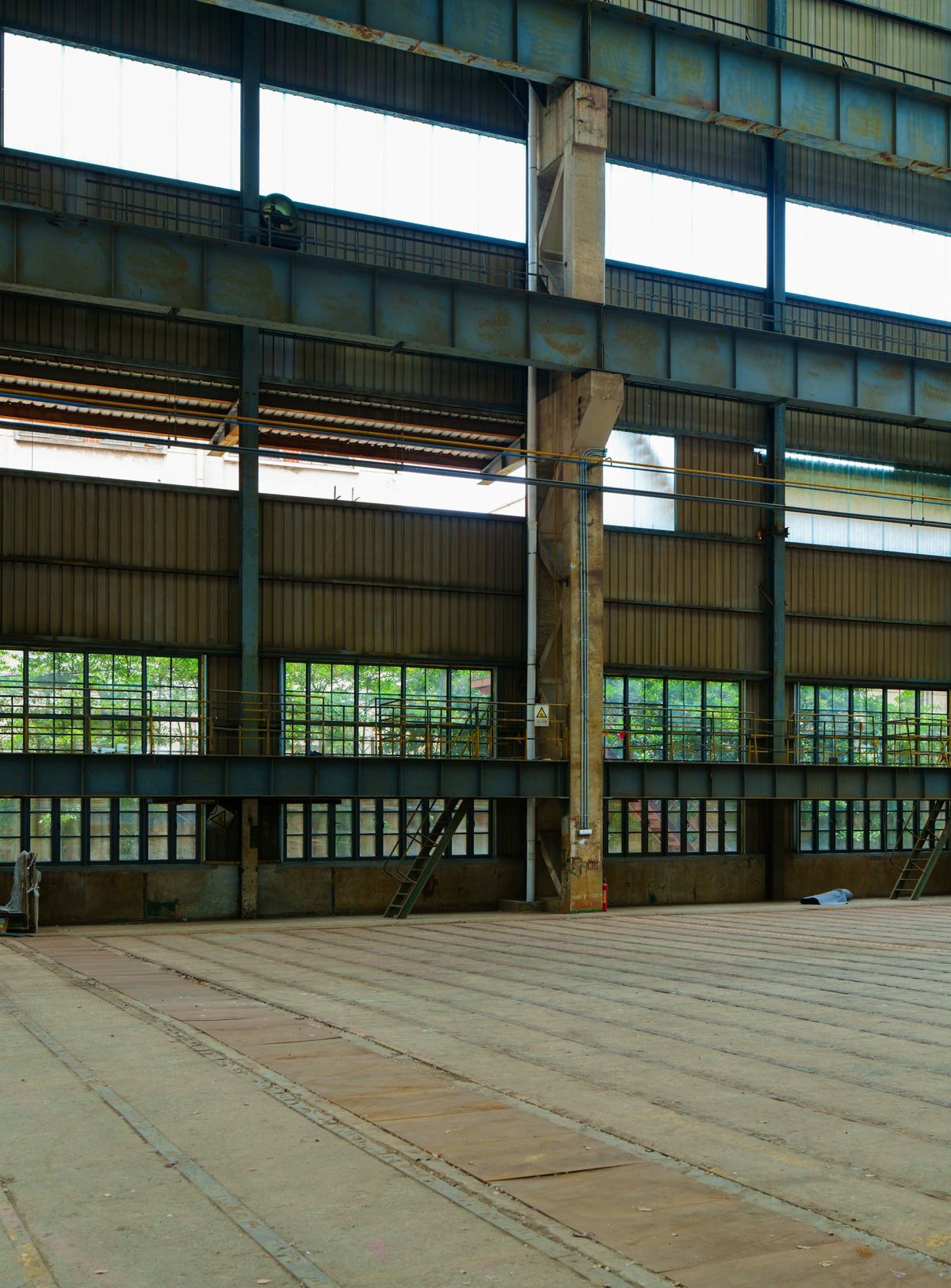 Stille, tom industrihall med stålbjelker og vinduer